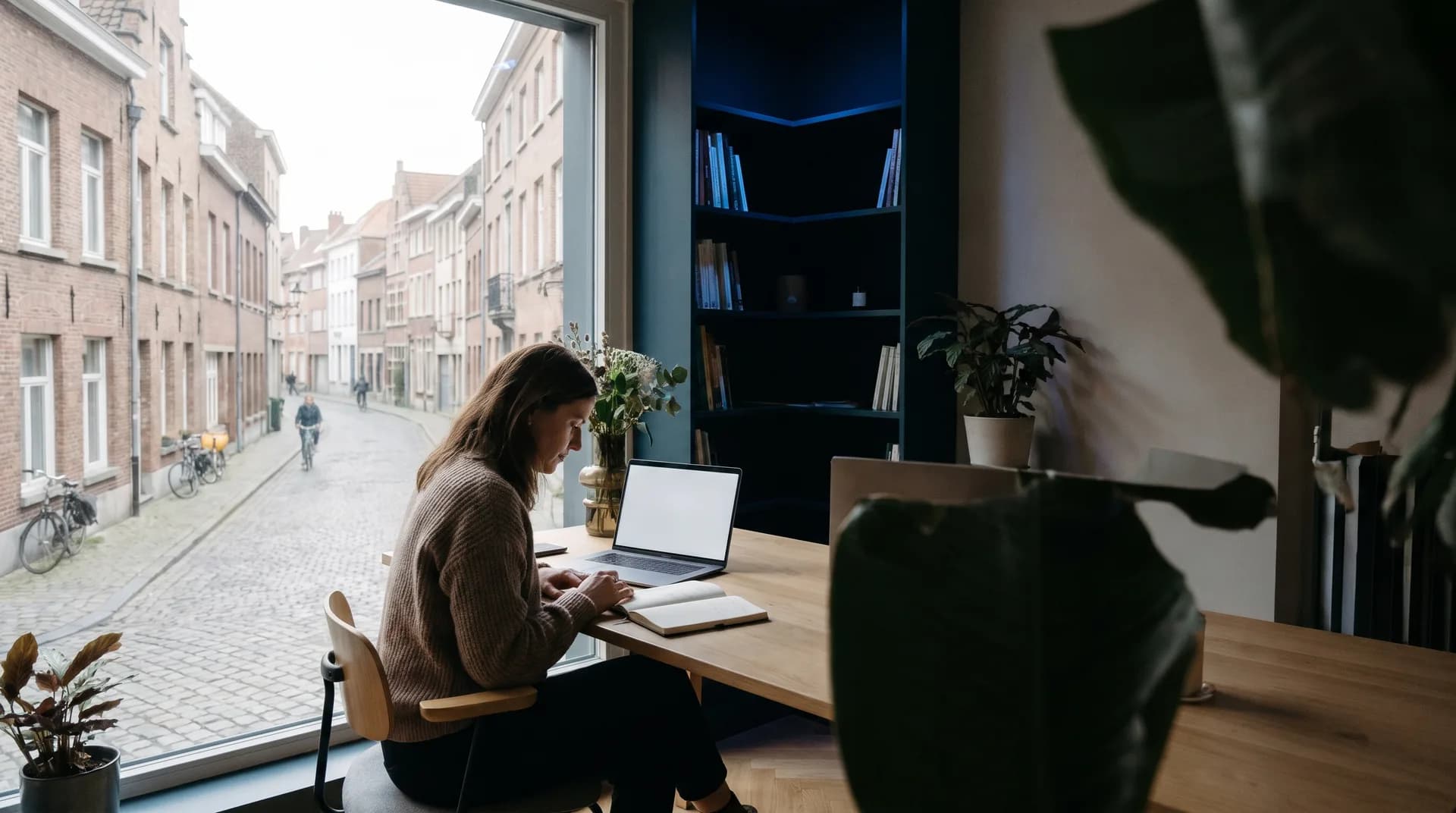Zaakvoerder van een Vlaamse kmo overloopt rustig haar werkdag aan een bureau met laptop en notitieboekje